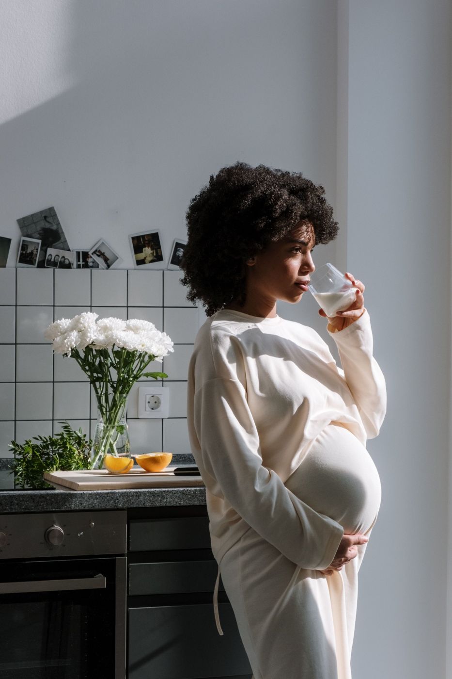 A pregnant woman in soft morning light, one hand resting on her belly