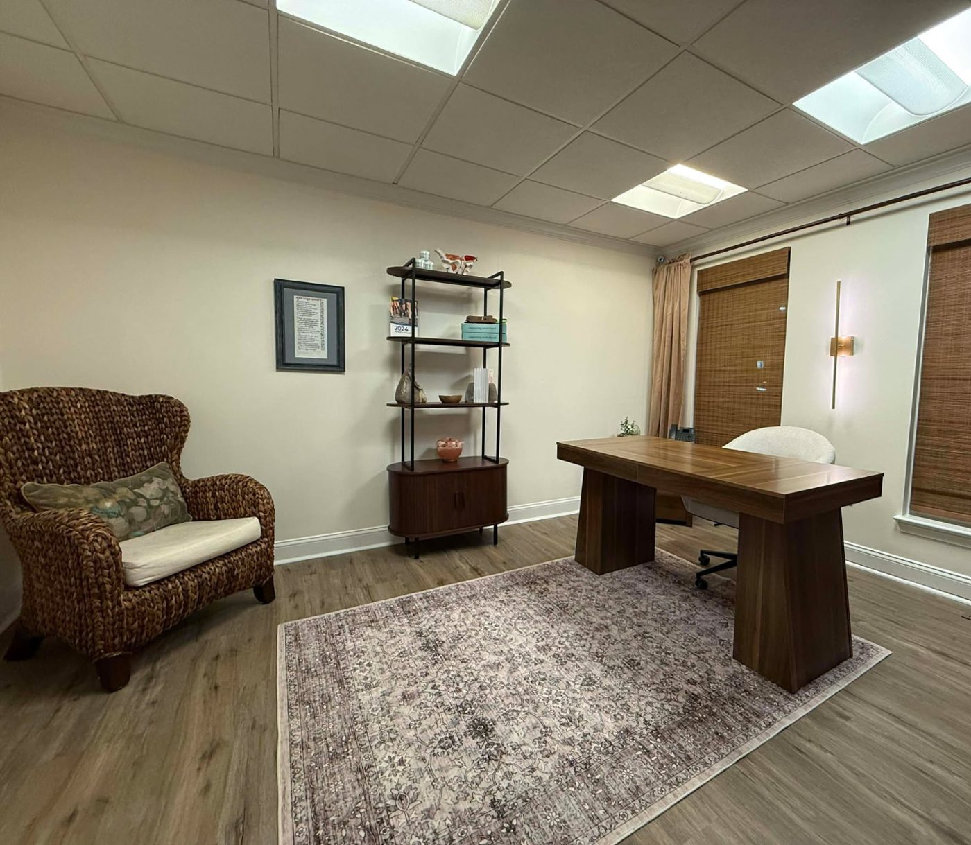 A calm treatment room with a wood desk, soft rug, and natural light